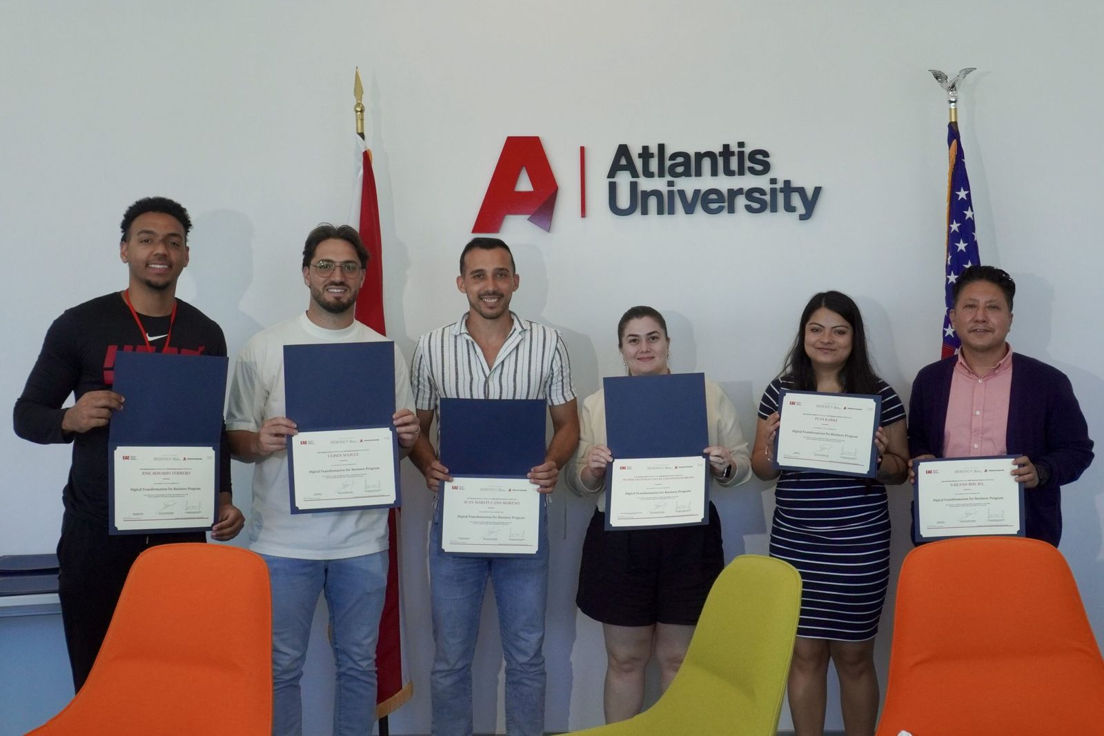 Students hold up their Digital Transformation certificates in front of the Atlantis University logo