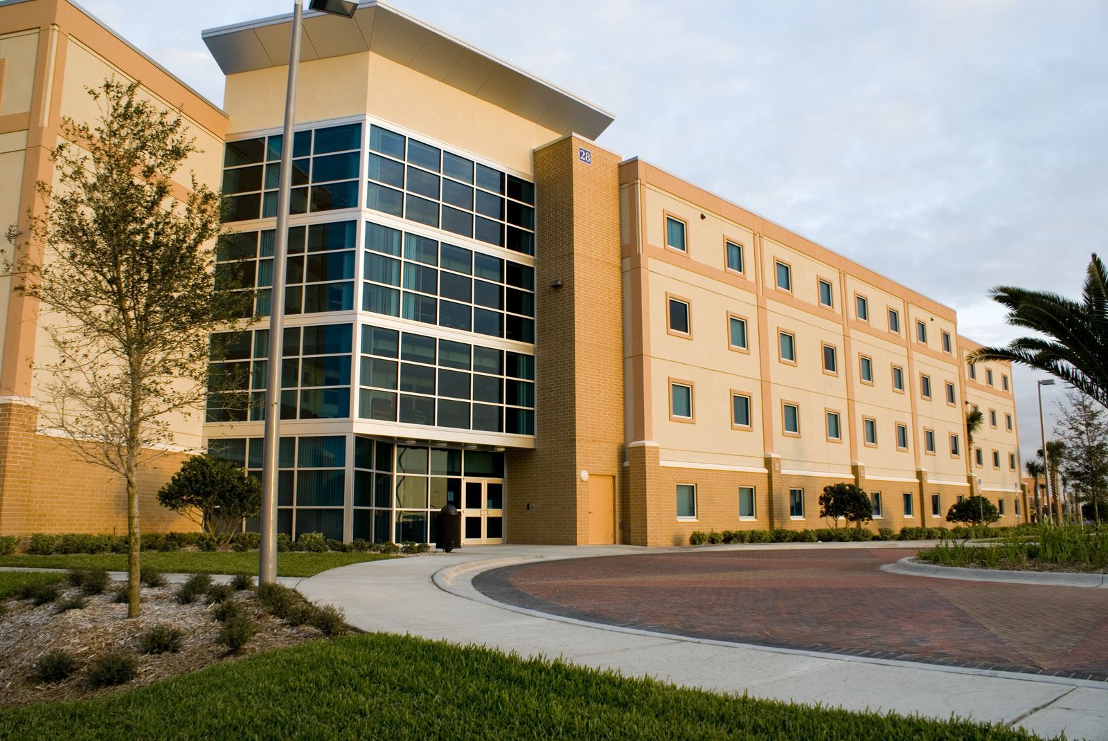 Exterior of Apollo Hall, the suite-style residence hall for second-year students at Embry-Riddle Daytona Beach, with a glass entrance and brick driveway