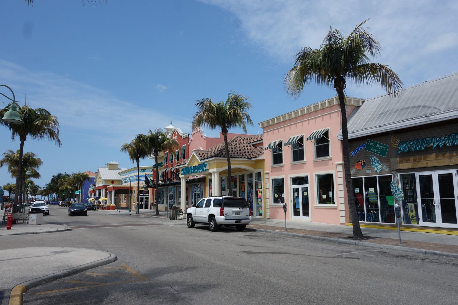 Street in historic downtown Fort Myers, with pastel-fronted shops, palm trees and parked cars on a sunny day