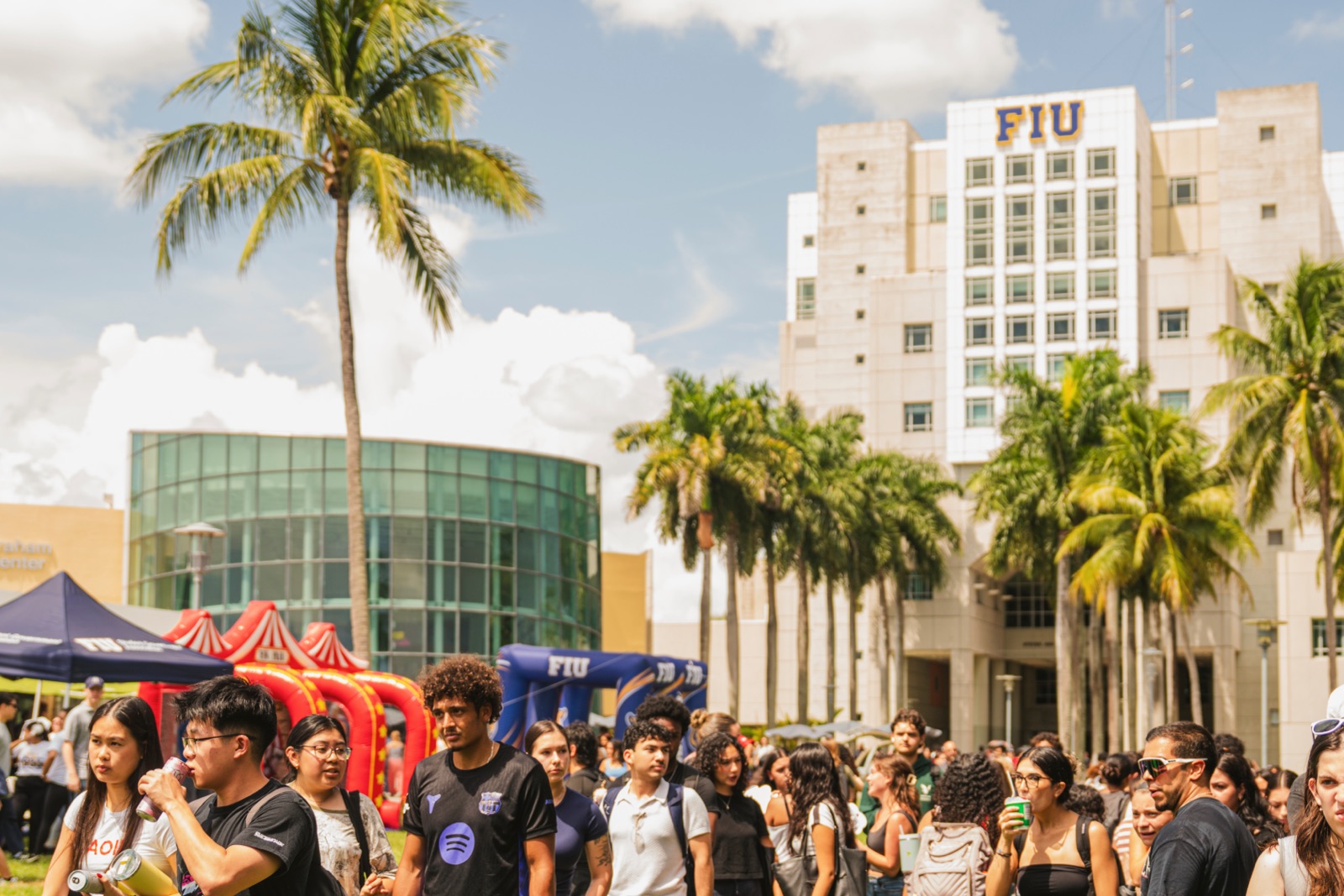 Students gathered in front of the Green Library, the tower with the FIU sign, among palm trees on the Modesto A. Maidique Campus in Miami