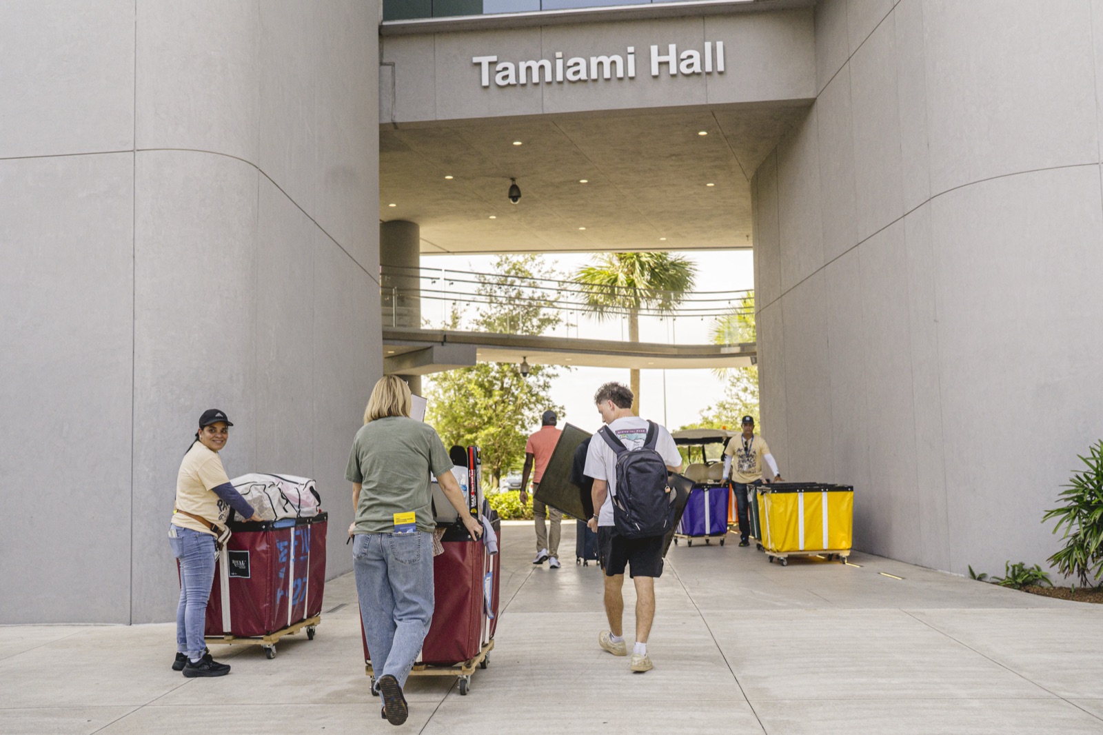 Families pushing moving carts into Tamiami Hall, an FIU residence hall, on move-in day