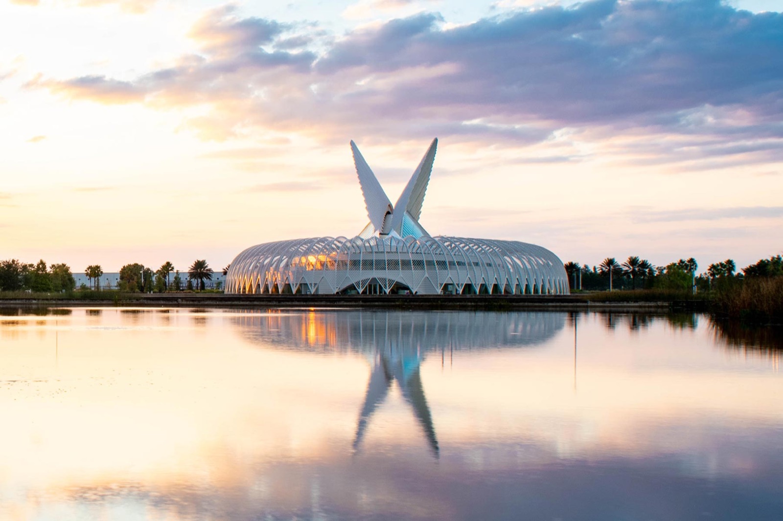 Florida Poly's IST Building at sunset, its movable wings reflected in the lake