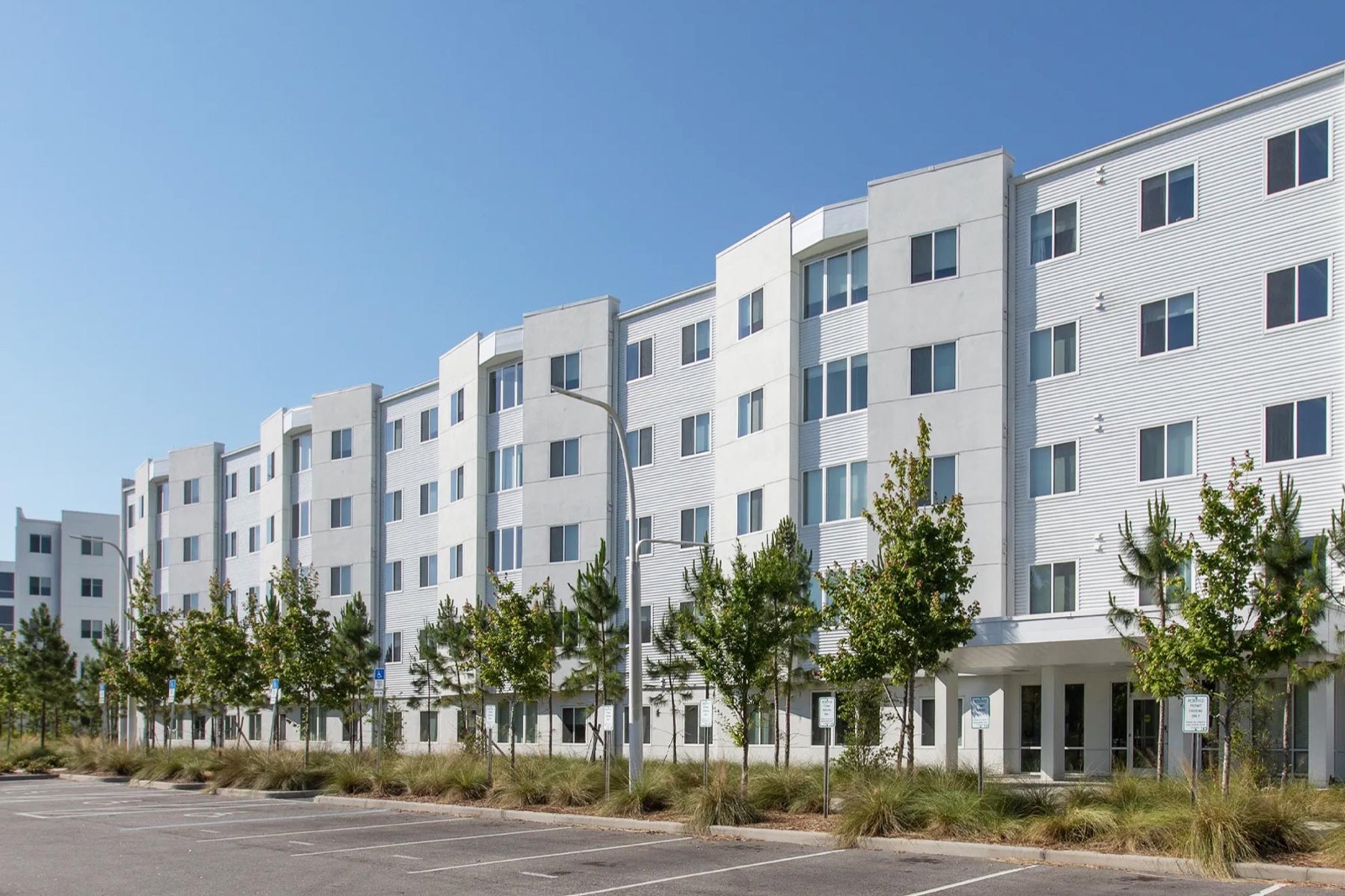 Exterior of Florida Poly's residence halls: four-storey white buildings with young trees beside the car park