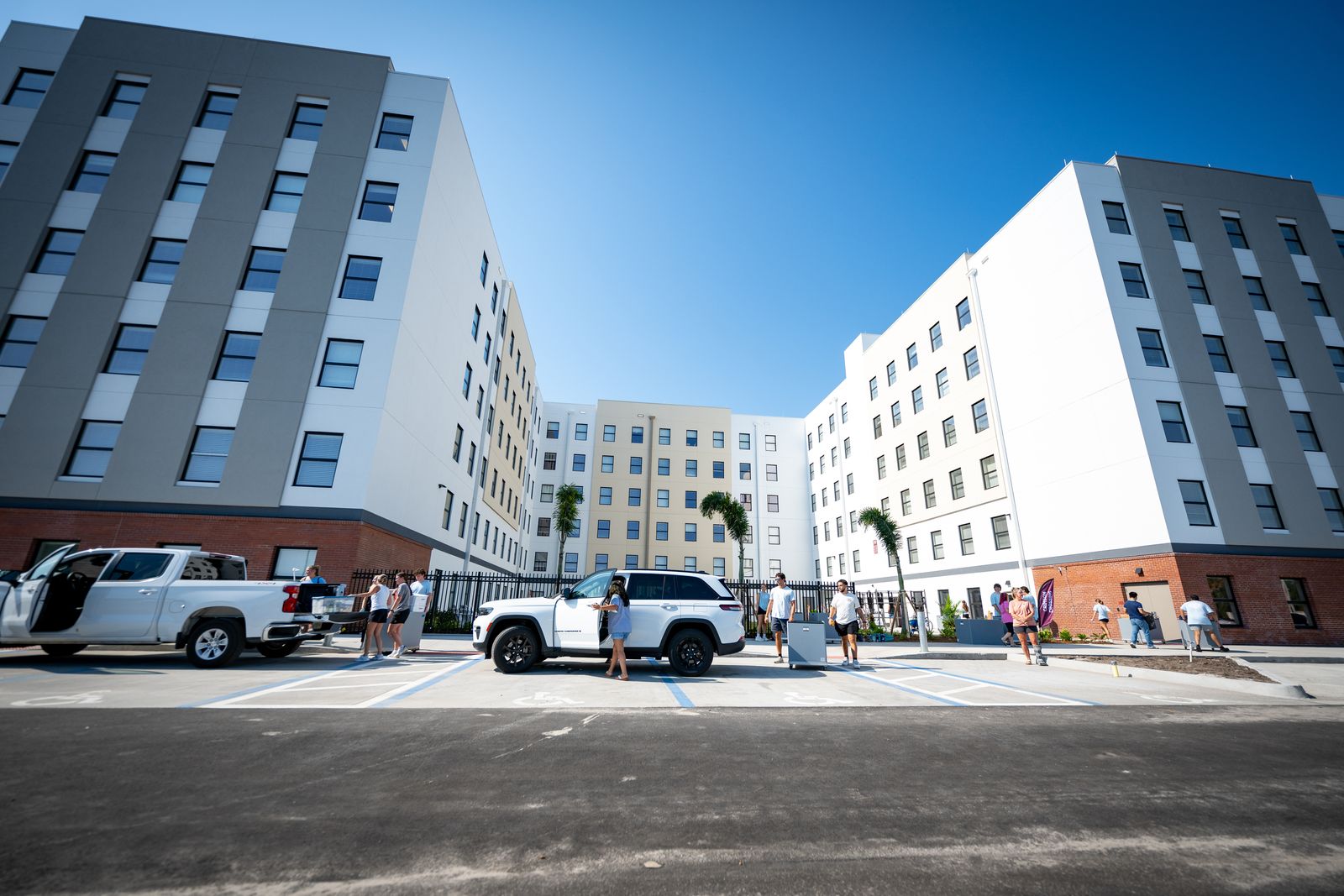 Exterior of the Crimson Crossing residence hall at Florida Tech on move-in day, with students and cars