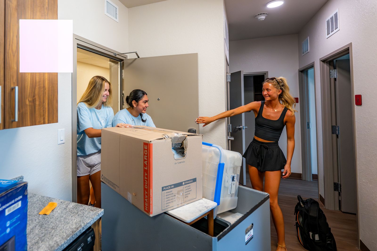 Students carry boxes into an apartment at the Crimson Crossing residence hall at Florida Tech