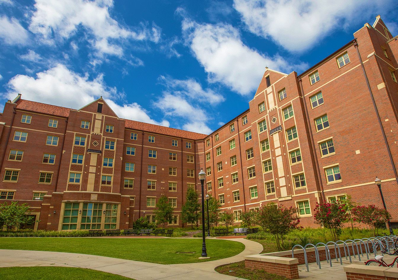 Azalea Hall, an FSU brick residence hall, seen from the inner lawn with walkways and a bike rack on a blue-sky day