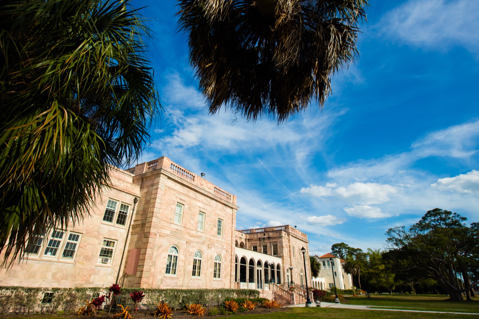 Front of College Hall, Charles Ringling's 1926 mansion that houses New College of Florida's welcome center, under a blue sky with palm trees