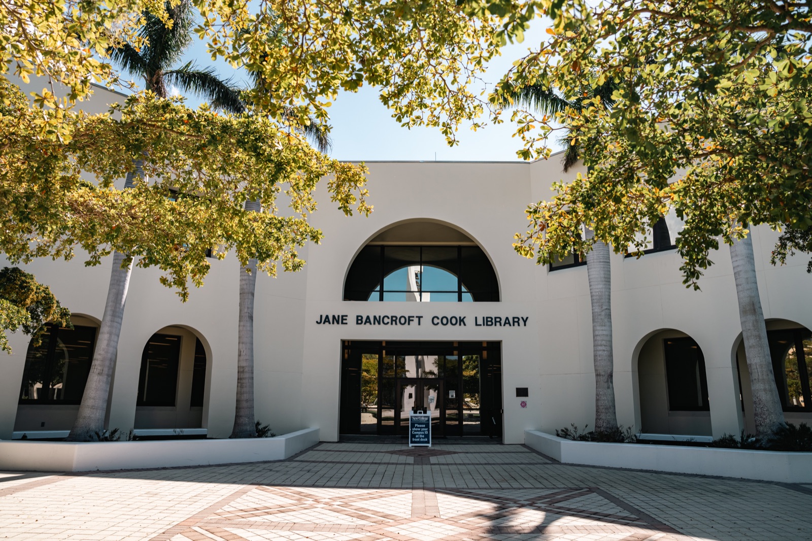 Entrance of the Jane Bancroft Cook Library, New College of Florida's library, with white arches and royal palms