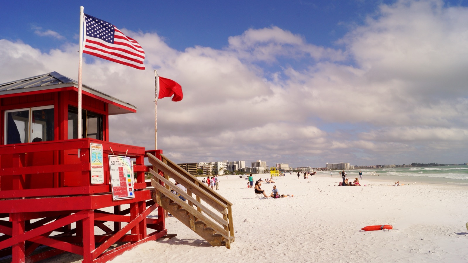 Red lifeguard stand on the white sand of Siesta Key Beach in Sarasota, with the Gulf of Mexico and a blue sky behind