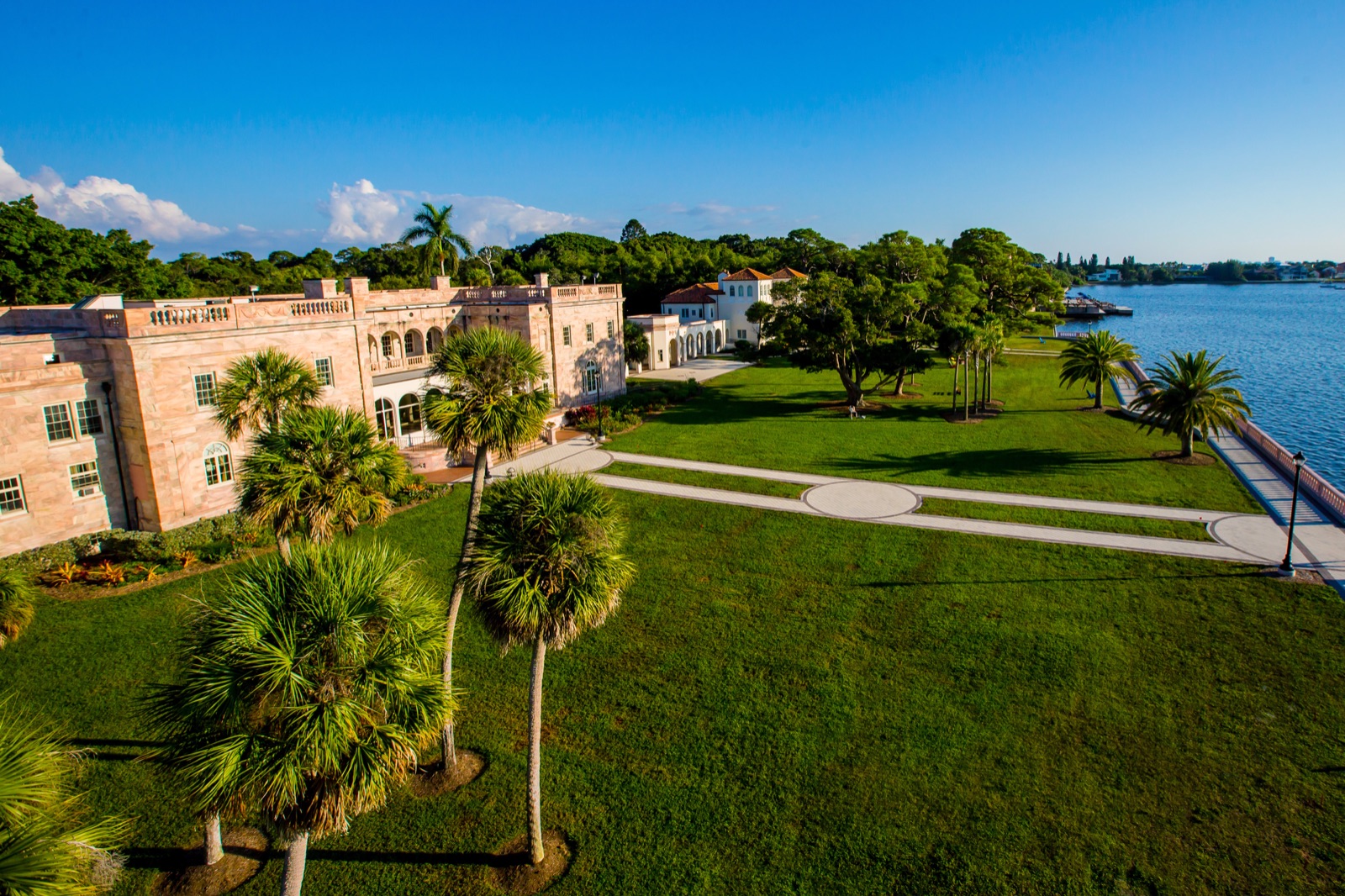 Aerial view of College Hall and Cook Hall, New College of Florida's historic mansions on Sarasota Bay, with the lawn, palm trees and the seawall