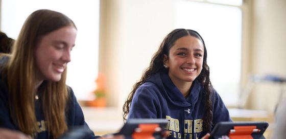 Dois alunos de moletom da Good Counsel sorrindo na sala de aula