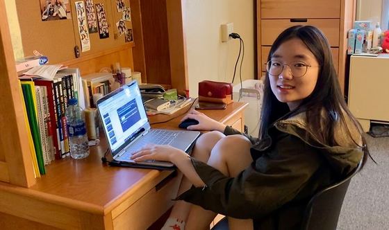 Aluna interna estudando no laptop na escrivaninha do quarto do dormitório