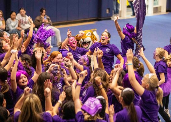 Alunas de roxo comemorando em um rally de espírito escolar