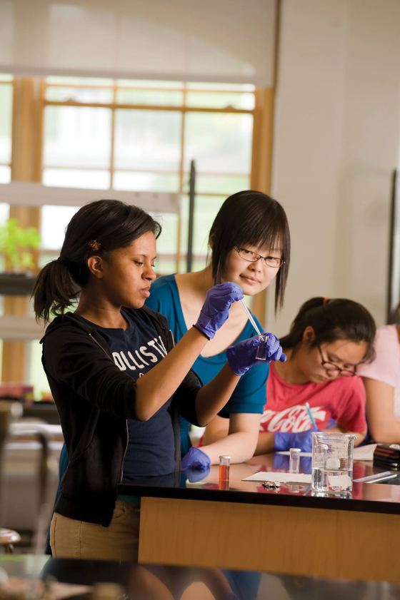 Alunas de luvas em um laboratório de ciências durante um experimento