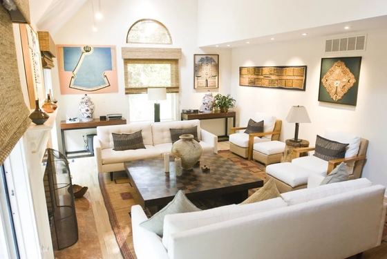 Sala de estar de uma casa de internato, com sofás brancos e quadros na parede