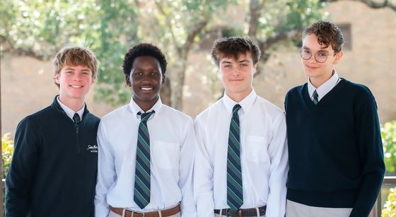 Quatro alunos do ensino médio de uniforme da SMA (gravata e suéter) ao ar livre no campus