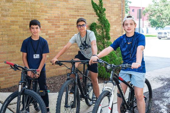 Três alunos internos com suas bicicletas no dia da mudança para o alojamento