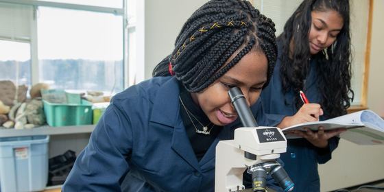 Duas alunas trabalhando com um microscópio no laboratório de ciências