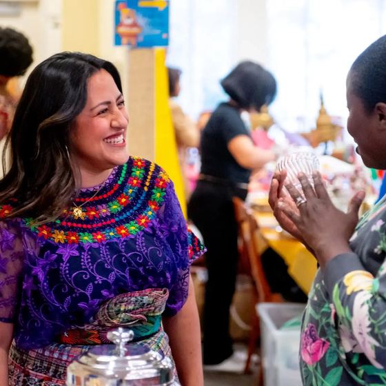 Mulher em traje tradicional guatemalteco em evento cultural no campus, com alunos