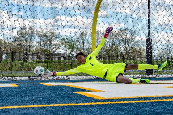 Goleiro do time de futebol do high school saltando para defender um chute