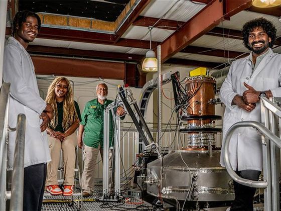 Estudantes e professores de jaleco ao lado dos equipamentos do Center for Plasma Science and Technology (CePaST) da FAMU