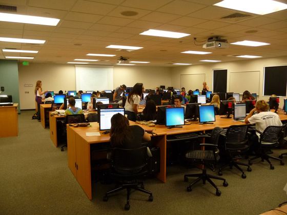 Estudantes trabalhando em computadores no laboratório de tutoria de matemática da FGCU. com fileiras de mesas e monitores