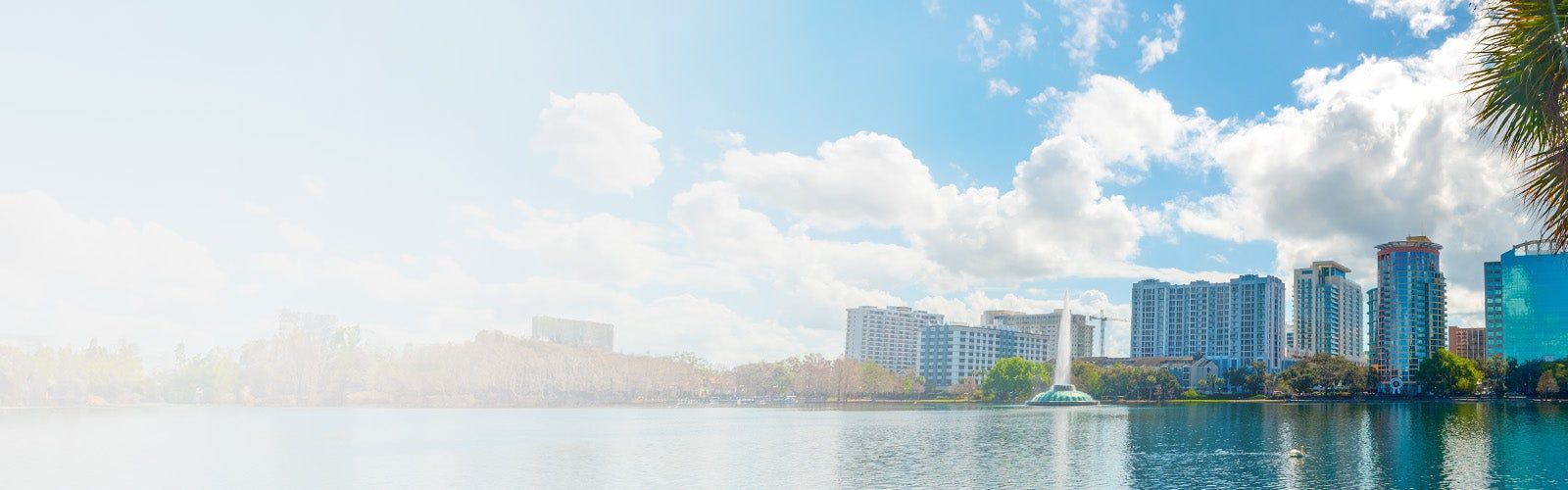 Lake Eola with its fountain and the downtown Orlando skyline under a blue sky