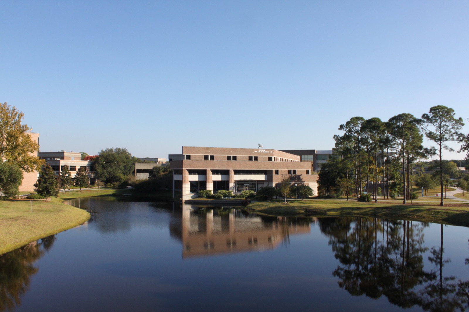 Coggin College of Business seen across the lake, among the pines of the UNF campus nature preserve
