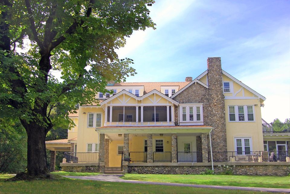 Casa de pedra e reboco amarelo que abriga o alojamento, vista do gramado