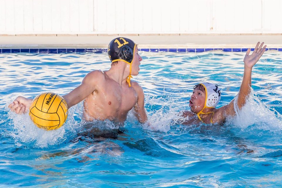 Cadete com a bola durante partida de polo aquático na piscina do campus