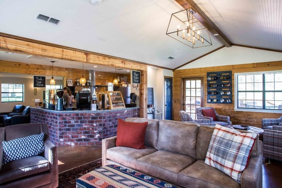 Sala de estar da casa de internato com balcão de café em tijolos, sofás e teto de madeira