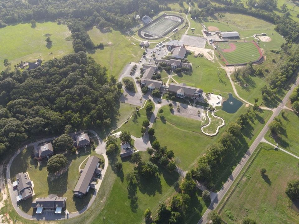 Vista aérea do campus com prédios acadêmicos, casas de internato, estádio e campos
