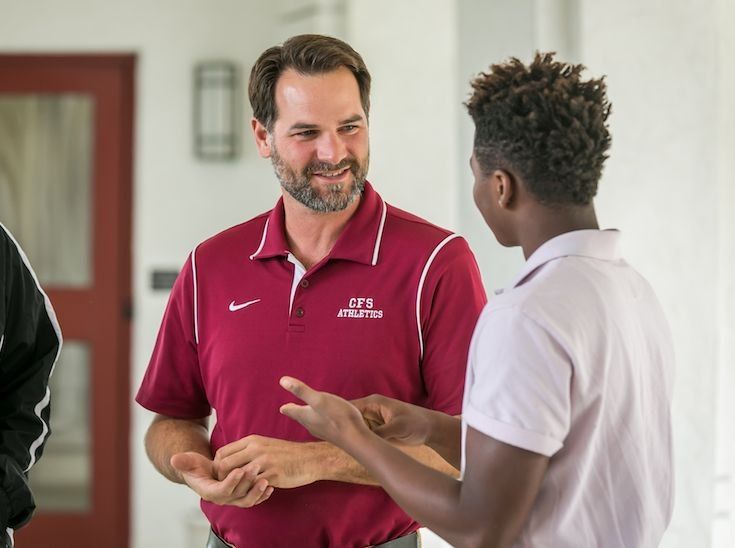 Aluno conversando com um funcionário do departamento esportivo na varanda de um prédio do campus