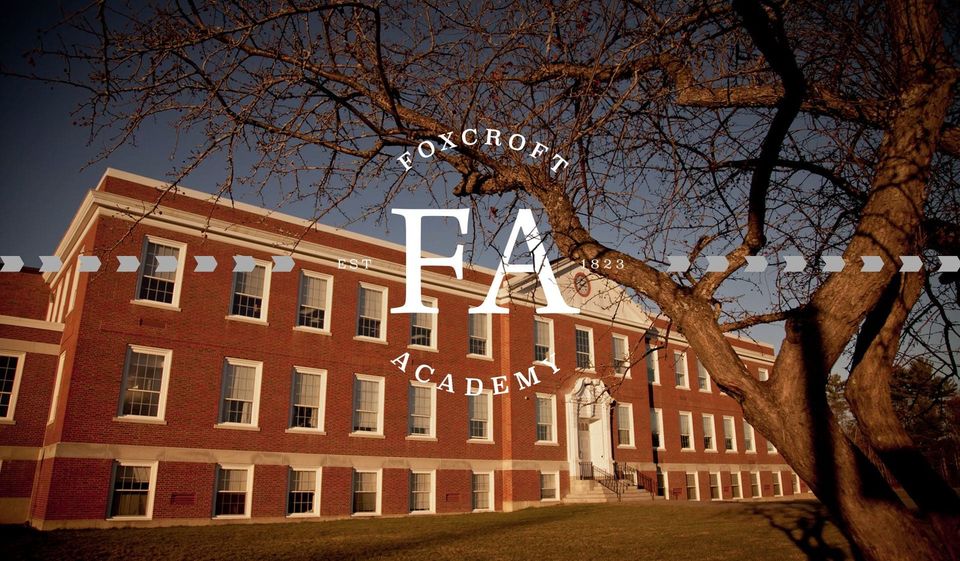 Prédio principal de tijolos da Foxcroft Academy à noite, com o logotipo da escola