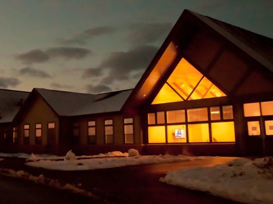 Alojamento Herd Hall iluminado à noite, com neve no chão