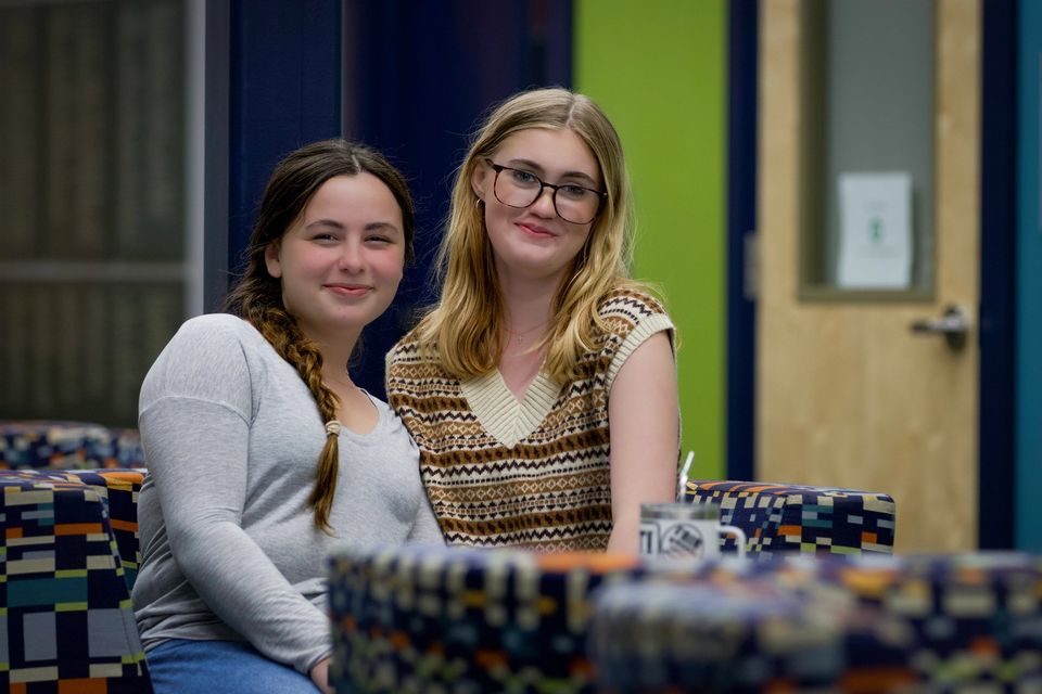 Duas alunas sentadas em um sofá colorido de uma sala comum