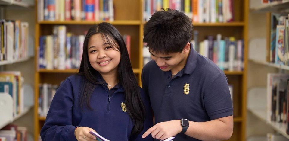 Dois alunos estudando juntos na biblioteca