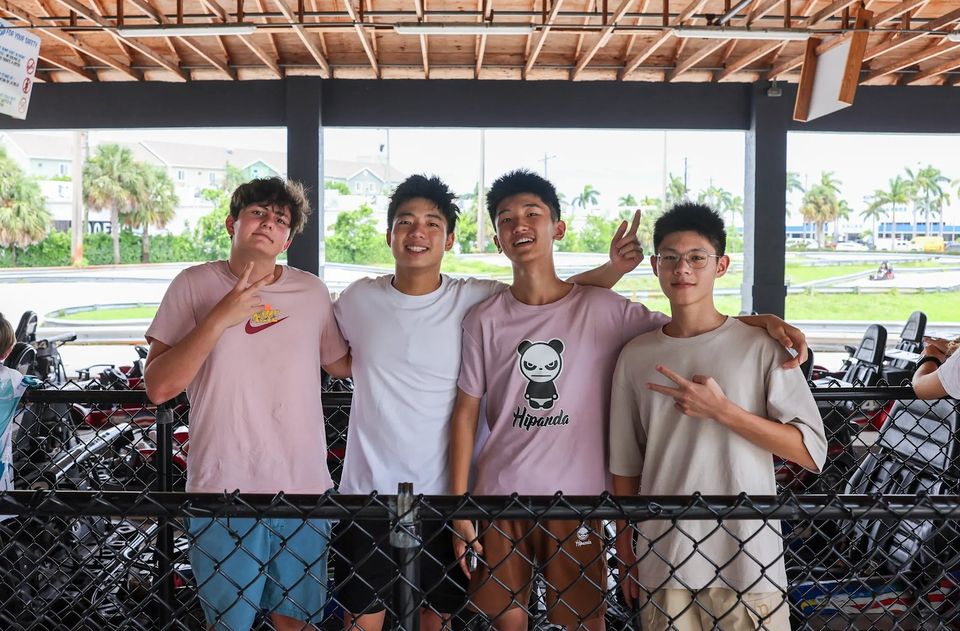 Quatro alunos internacionais posando em um passeio de fim de semana em uma pista de kart