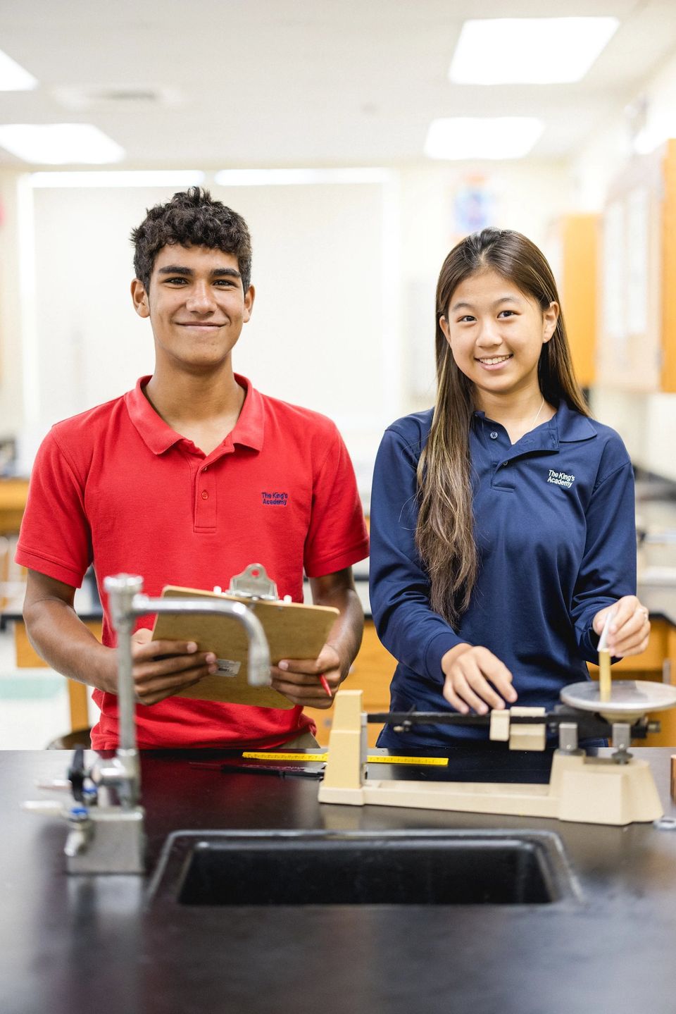 Dois alunos do ensino médio de polo da TKA em uma bancada de laboratório com uma balança
