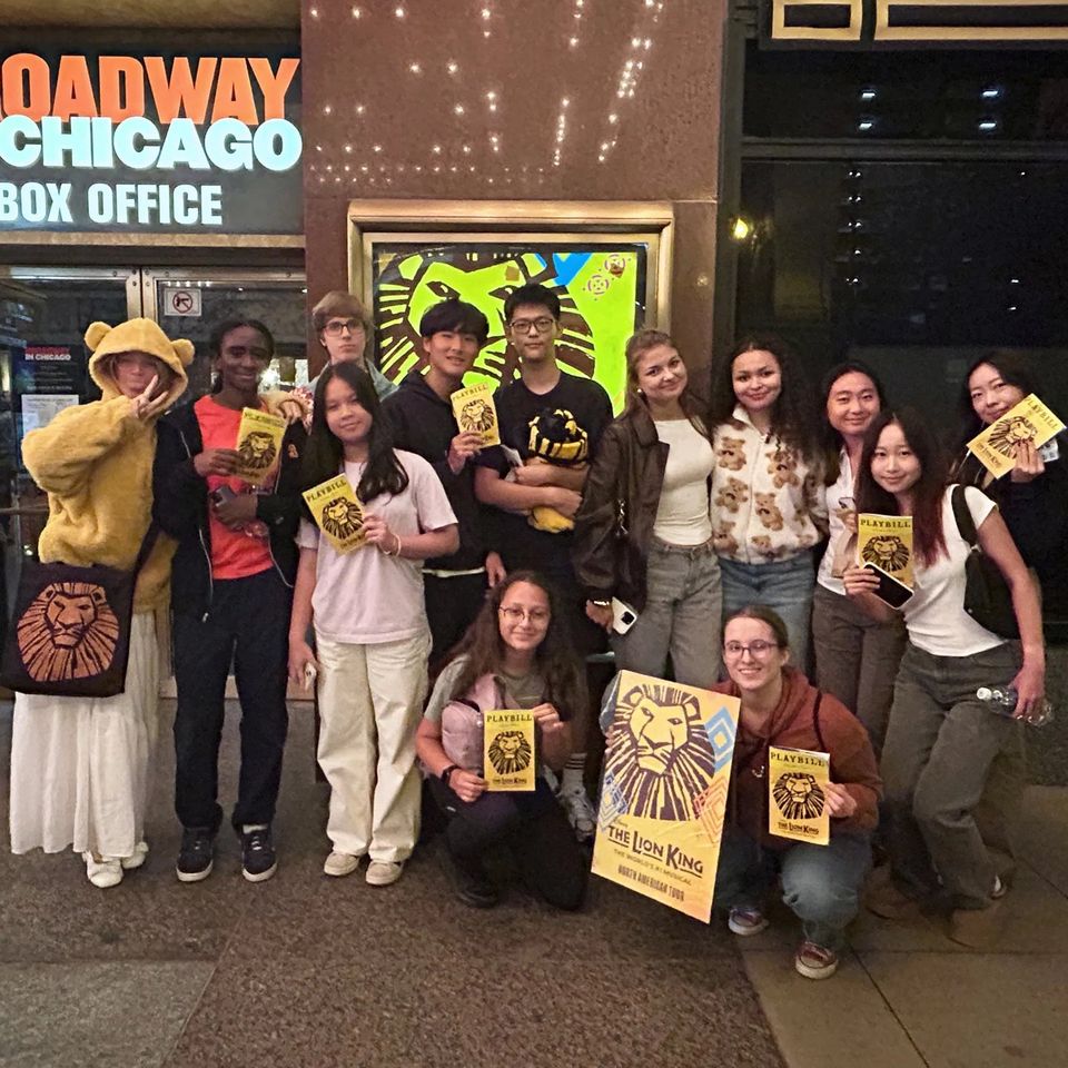 Alunos internos com programas do musical O Rei Leão em frente ao teatro em Chicago, em passeio de fim de semana