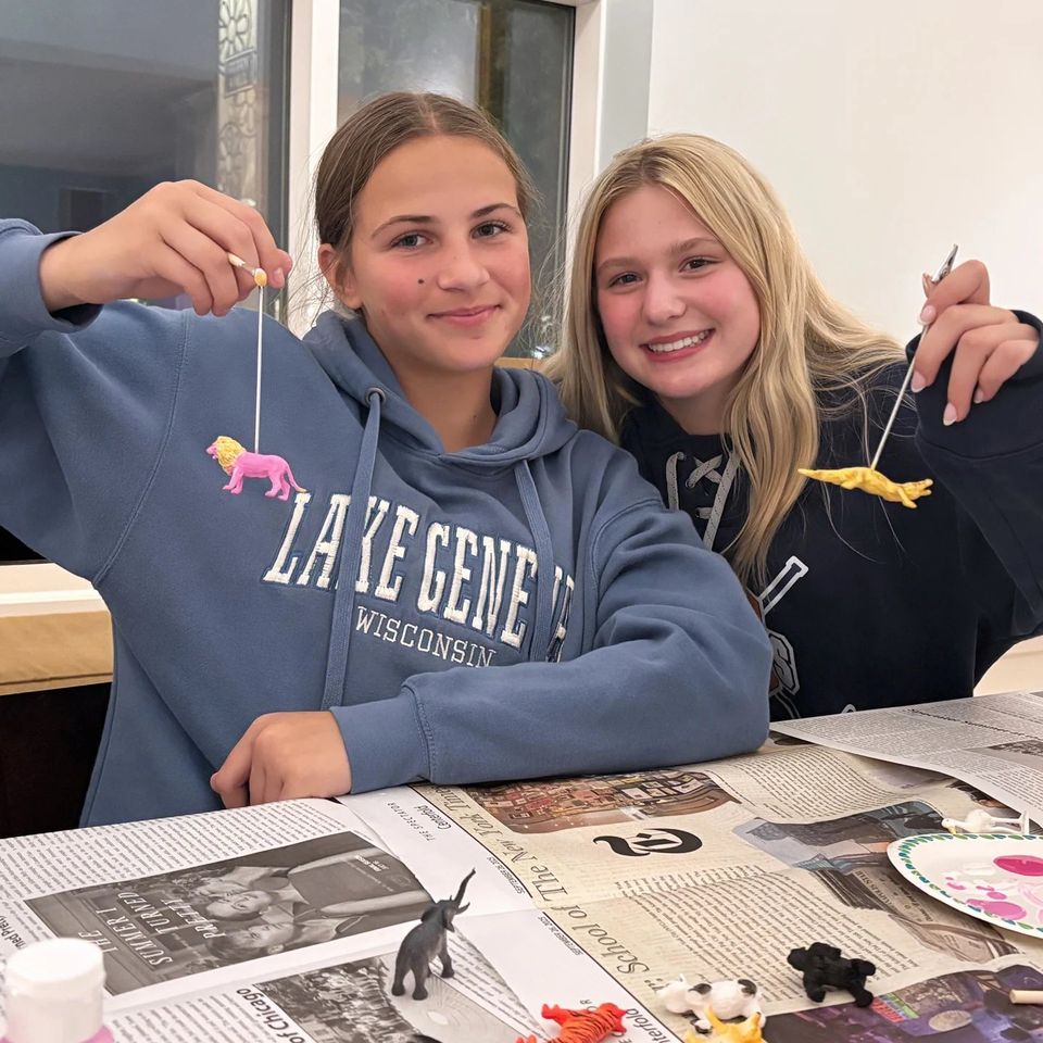 Dois alunos pintando miniaturas de animais em atividade de artesanato no fim de semana