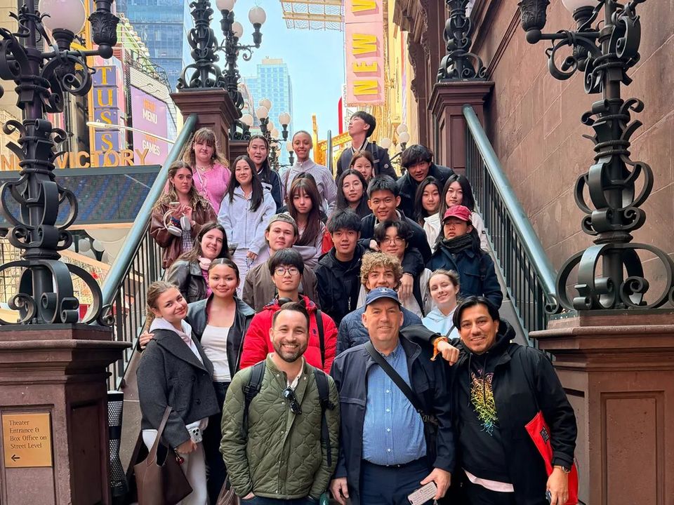 Alunos do coral e professores na escadaria de um teatro durante a viagem a Nova York