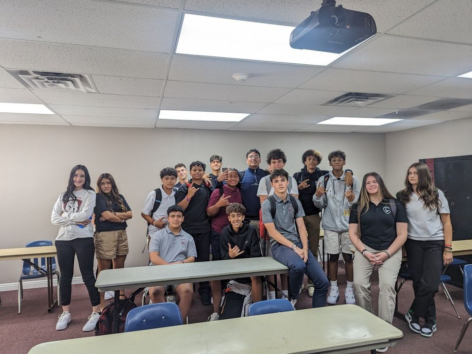 Alunos do ensino médio de polo uniforme posando em uma sala de aula