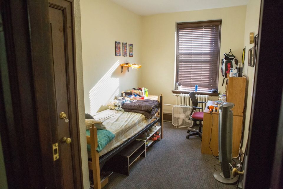 Quarto de alojamento com cama, mesa de estudo, cadeira e janela com persiana