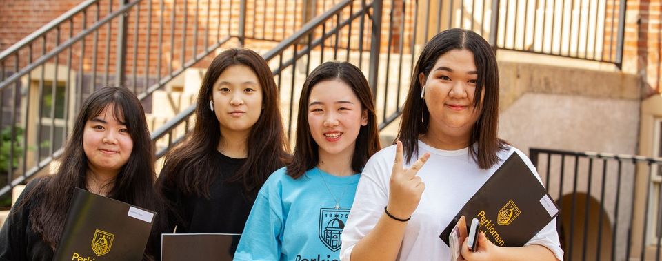 Quatro alunos internacionais segurando certificados/diplomas no campus