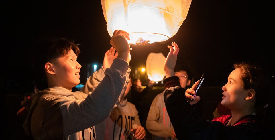 Alunos soltando uma lanterna de papel à noite