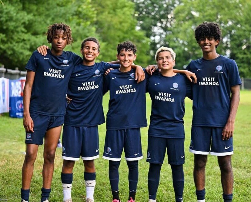 Cinco jogadores da Academy Pro de uniforme de treino do PSG, abraçados no gramado