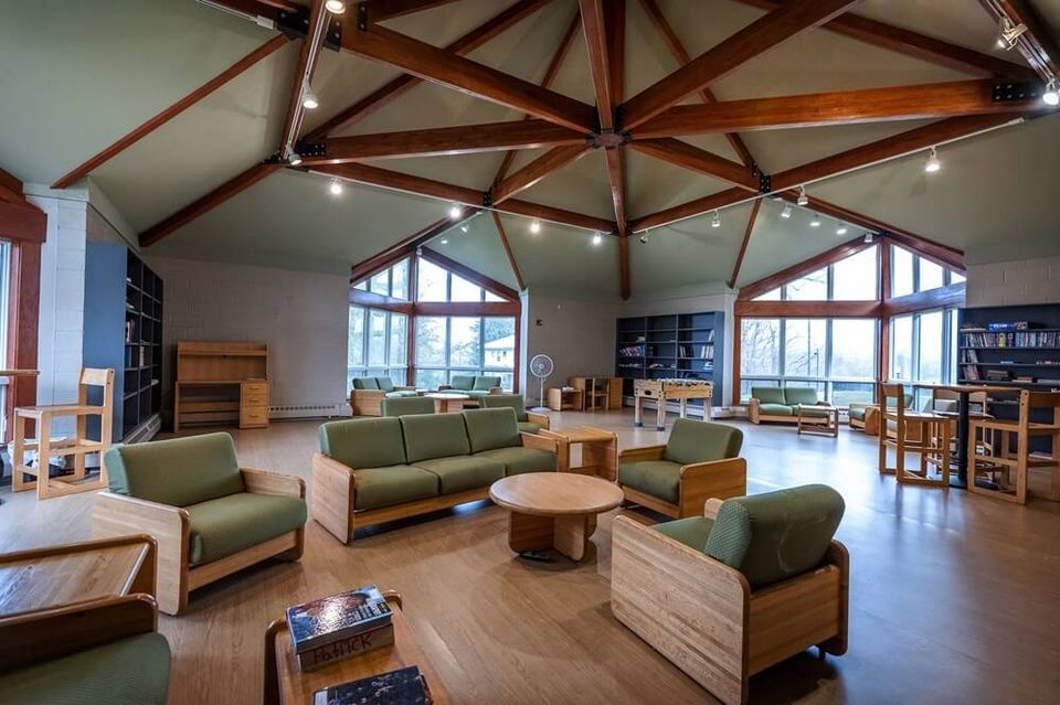 Sala de convivência do dormitório com sofás, estantes e mesa de pebolim