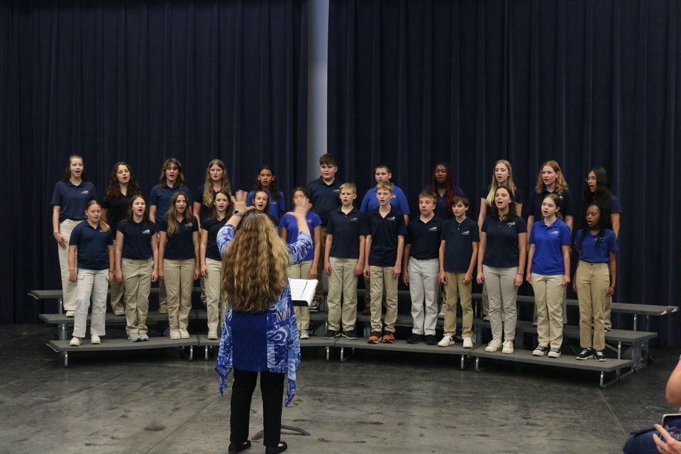 School choir performing on risers with a conductor