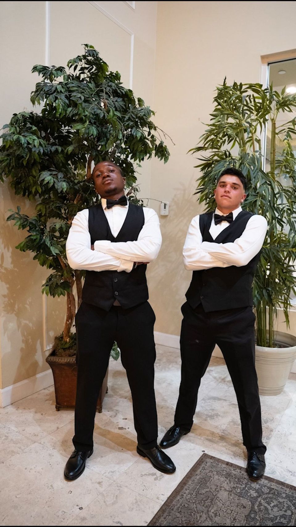 Dois meninos de colete e gravata-borboleta posando antes de um evento formal
